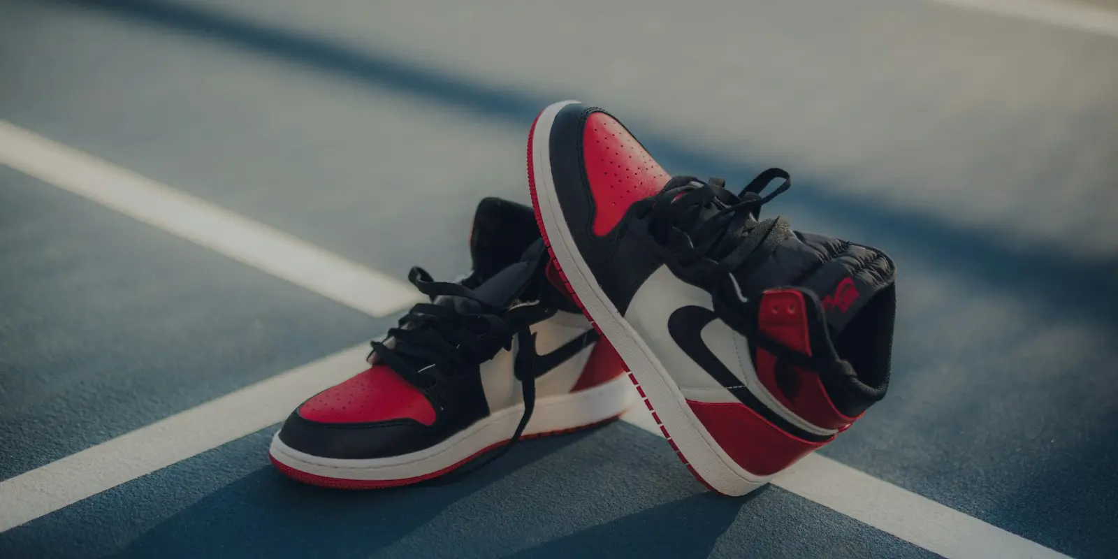 Pereche de sneakers înalți roșu cu negru și alb, pe un teren de sport