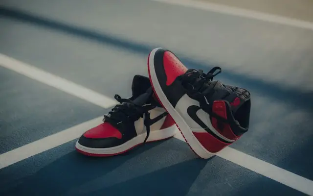 Pereche de sneakers înalți roșu cu negru și alb, pe un teren de sport