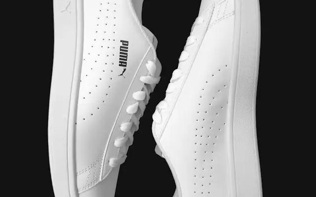 Pereche de sneakers albi cu tălpi albe pe fundal închis